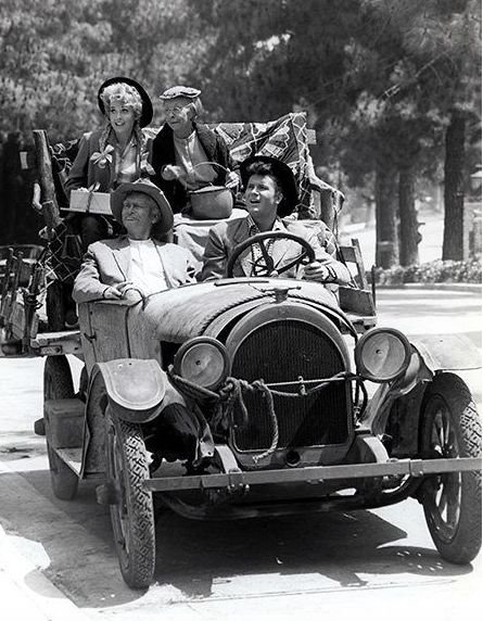 This may contain: black and white photograph of people riding in an old car