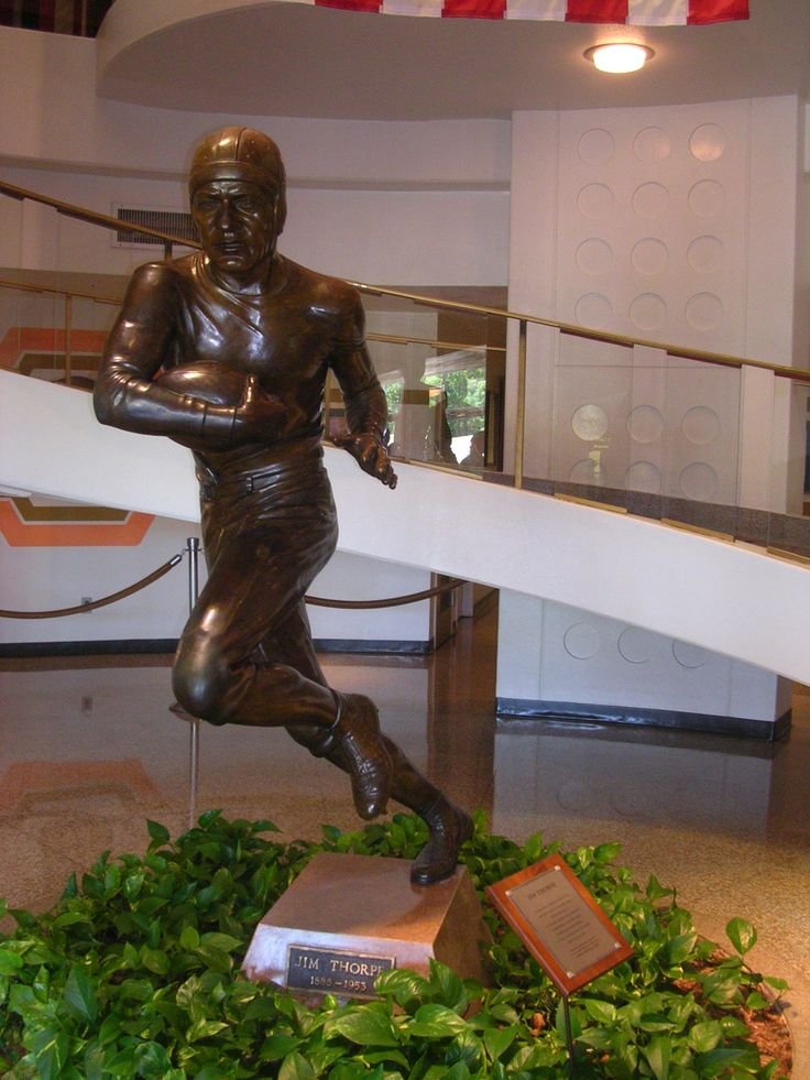 This may contain: a statue of a football player is in the middle of a room with greenery